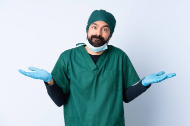 Yeşil üniformalı bir cerrah soyutlanmış geçmişinden şüphe duyuyor ve ellerini kaldırıyor.