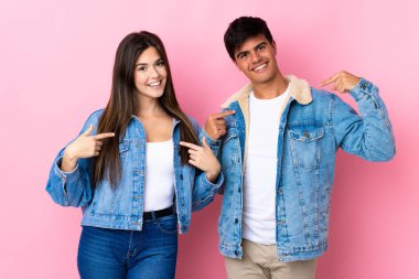Soyutlanmış pembe arka planı olan genç bir çift gururlu ve kendini beğenmiş bir aşk konsepti.