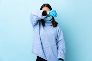 Genç esmer, melez bir kadın. Koronavirüsten koruyor. Maske ve eldivenlerle.