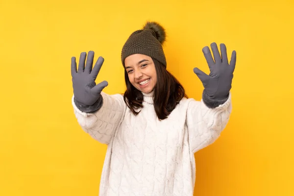 年轻女子头戴冬帽 黄底孤立 手指数十 — 图库照片