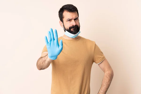 一个白种人 留着胡子 戴着面具和手套 在孤立的背景下保护自己不受考拉威斯的伤害 — 图库照片