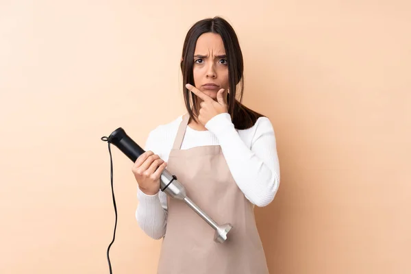 Jovem Morena Usando Liquidificador Mão Sobre Fundo Isolado Pensando — Fotografia de Stock