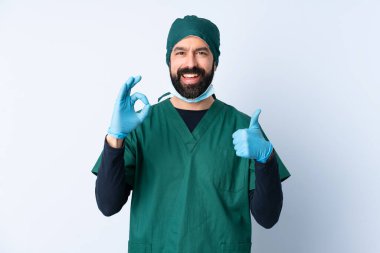 Yeşil üniformalı bir cerrah izole edilmiş bir zeminde işaret ve işaret işareti gösteriyor.