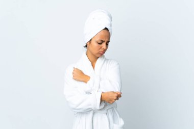 Bornozlu genç bir kadın soyutlanmış beyaz bir arka plan ve dirsek ağrısı var.