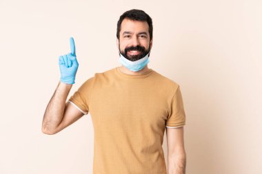 Sakallı, maskeli ve eldivenli beyaz adam harika bir fikre işaret ediyor.