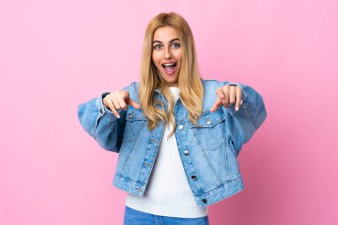 Genç Uruguaylı sarışın kadın izole pembe arka planda şaşırmış ve ön tarafı işaret ediyor.