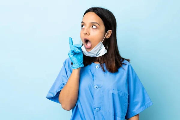 指を指差すアイデアを考える隔離された青い背景の外科医の女性 — ストック写真
