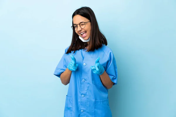 一位外科医生站在孤立的蓝色背景上 指着前面笑着 — 图库照片