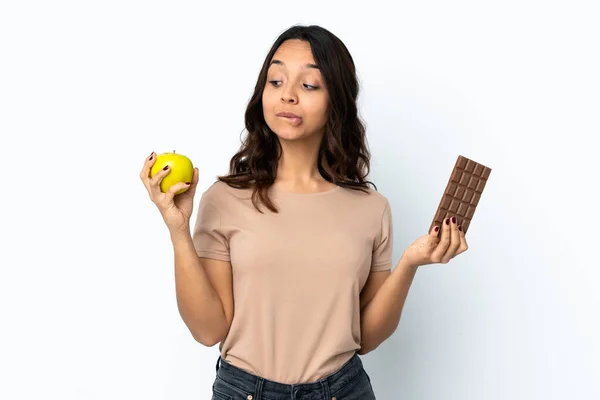 Mladá Žena Izolovaném Bílém Pozadí Pochybnostmi Při Užívání Čokoládové Tablety — Stock fotografie