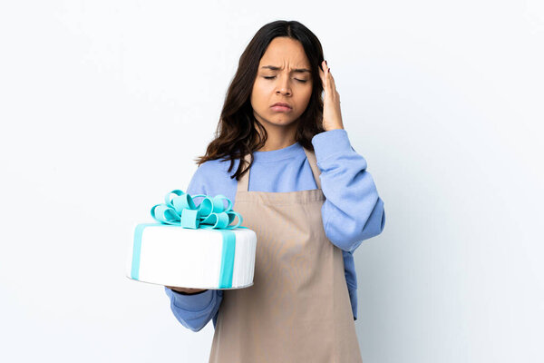 Pastry chef holding a big cake over isolated white background with headache