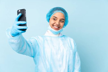Mavi üniformalı genç cerrah Hintli kadın selfie çekiyor.