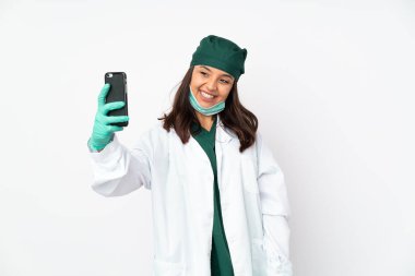 Yeşil üniformalı kadın, beyaz arka planda izole edilmiş bir şekilde selfie çekiyor.