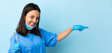 Genç esmer, melez bir dişçi kadının elinde izole edilmiş arka planda aletler var.