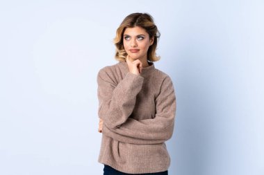 Genç Rus kadın mavi arka planda izole edilmiş. Şüpheleri ve düşünceleri var.