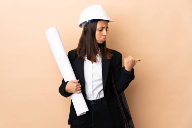 Genç mimar kadının elinde izole edilmiş arka planla ilgili planlar var. Mutsuz ve kenarı işaret ediyor.