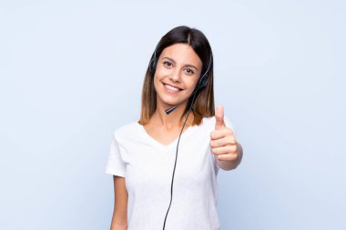 Soyutlanmış mavi geçmişi olan genç bir kadın başparmağıyla kulaklıkla çalışıyor.