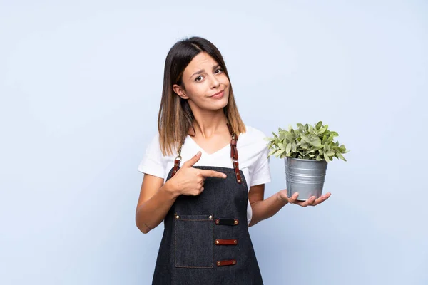 Jovem Mulher Sobre Isolado Azul Fundo Tomando Vaso Flores Apontando — Fotografia de Stock