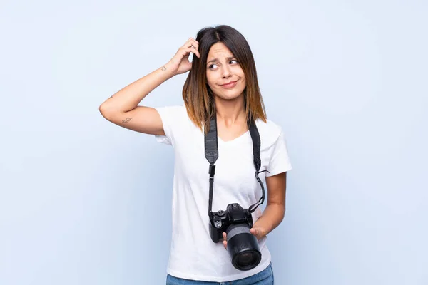 Jonge Vrouw Geïsoleerde Blauwe Achtergrond Met Een Professionele Camera Denken — Stockfoto