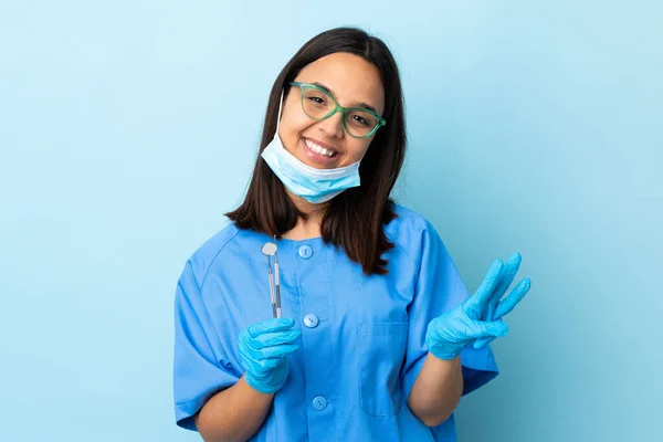 年轻的黑发男女混血的牙医女人快乐地拿着工具盖住孤立的背景 用手指数着三个 — 图库照片