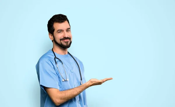 Lekarz Chirurg Człowiek Prezentując Pomysł Patrząc Uśmiechnięty Ponad Odizolowanym Niebieskim — Zdjęcie stockowe