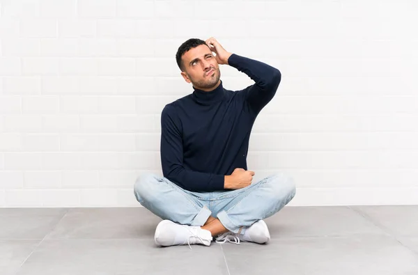 Joven Hombre Guapo Sentado Suelo Teniendo Dudas Con Expresión Cara — Foto de Stock