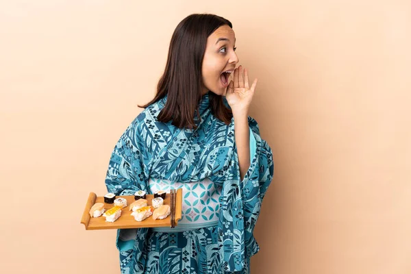 Frau Trägt Kimono Und Hält Sushi Über Isoliertem Hintergrund Und — Stockfoto