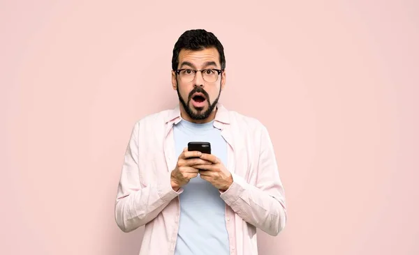 Hombre Guapo Con Barba Sorprendido Enviando Mensaje Sobre Fondo Rosa —  Fotos de Stock