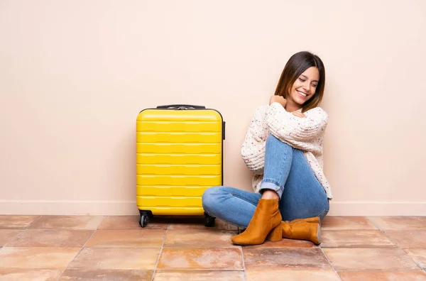 Traveler woman with suitcase sitting on the floor laughing