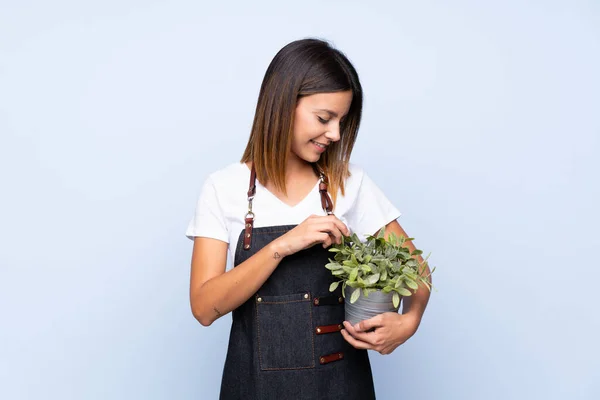 Ung Kvinna Över Isolerad Blå Bakgrund Tar Blomkruka — Stockfoto