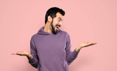 Eşofmanlı yakışıklı bir adam. Kopyalama alanı tutuyor. İki eli de izole edilmiş pembe arka planı var.