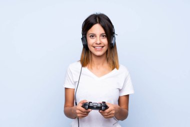 İzole edilmiş mavi arka plan video oyunlarında oynayan genç bir kadın.