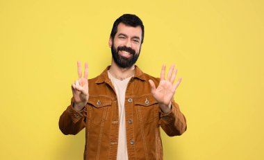 Sakallı yakışıklı adam yediyi parmaklarıyla sayıyor.