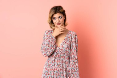 Pembe arka planda izole edilmiş genç bir Rus kadın yan bakıyor ve gülümsüyor.