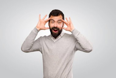 Gri arka planda sürpriz ifadesi olan yakışıklı bir adam.