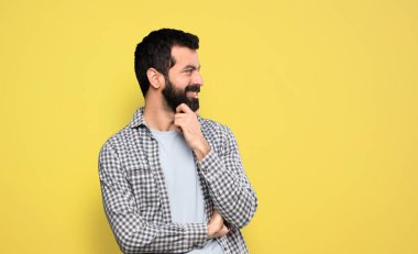 Sakallı yakışıklı adam yan tarafa bakıyor.