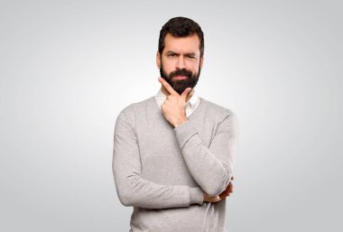 Gri arka plan üzerinde düşünen yakışıklı bir adam.