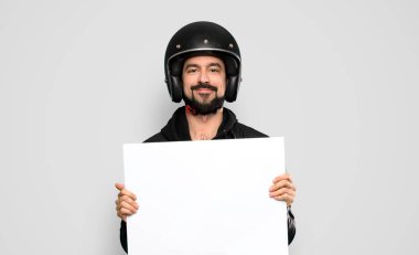 Biker man holding an empty placard over isolated grey background