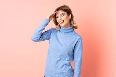 Pembe arka planda izole edilmiş genç bir Rus kadın bir şeye bakmak için çok uzaklara bakıyor.