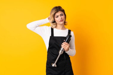 Sarı arkaplanda izole edilmiş el blenderi kullanan kızın şüpheleri var