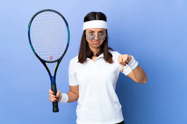 Young woman tennis player over isolated background making good-bad sign. Undecided between yes or not