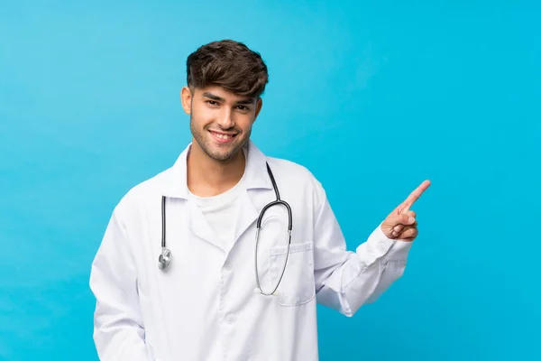 Joven Hombre Guapo Sobre Fondo Azul Aislado Con Bata Médico — Foto de Stock