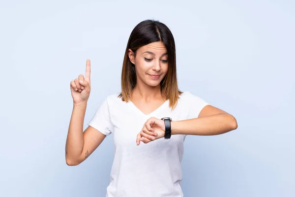 Jovem Mulher Sobre Fundo Azul Isolado Olhando Para Relógio Mão — Fotografia de Stock