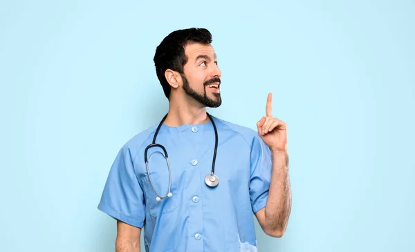 外科医の男は指を指すアイデアを考える隔離された青の背景 — ストック写真