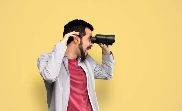 Bello Uomo Con Barba Con Binocolo Sfondo Giallo Isolato — Foto Stock