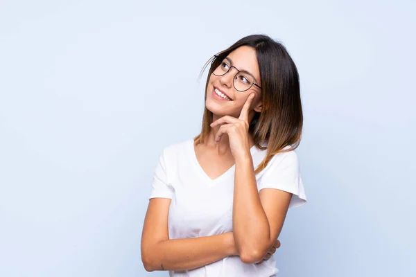 Gözlüklü Soyutlanmış Mavi Arka Planı Olan Genç Bir Kadın — Stok fotoğraf