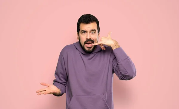 Knappe Man Met Sweatshirt Maken Telefoon Gebaar Twijfelen Geïsoleerde Roze — Stockfoto