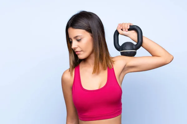 Mujer Deportiva Joven Sobre Fondo Azul Aislado Haciendo Levantamiento Pesas —  Fotos de Stock