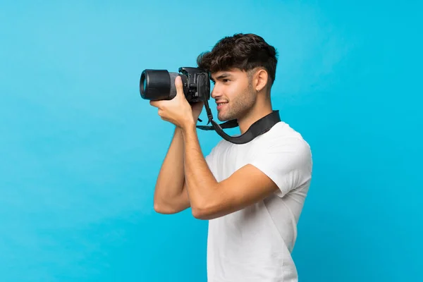 Giovane Bell Uomo Sfondo Blu Isolato Con Una Fotocamera Professionale — Foto Stock