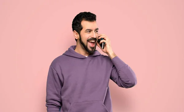 Sweatshirt Yakışıklı Bir Adam Cep Telefonuyla Pembe Arka Planda Sohbet — Stok fotoğraf