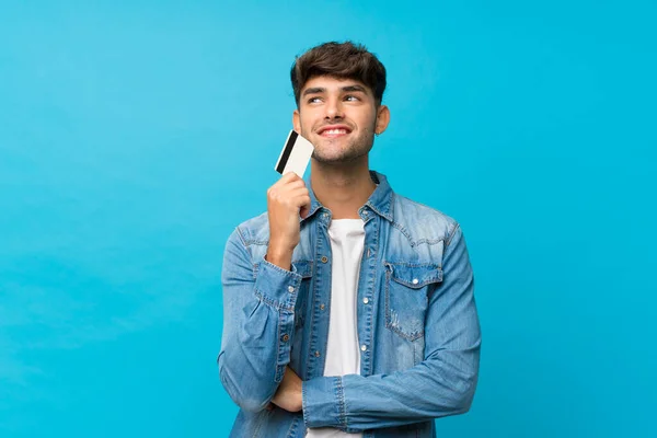Junger Gutaussehender Mann Über Isoliertem Blauem Hintergrund Mit Kreditkarte — Stockfoto